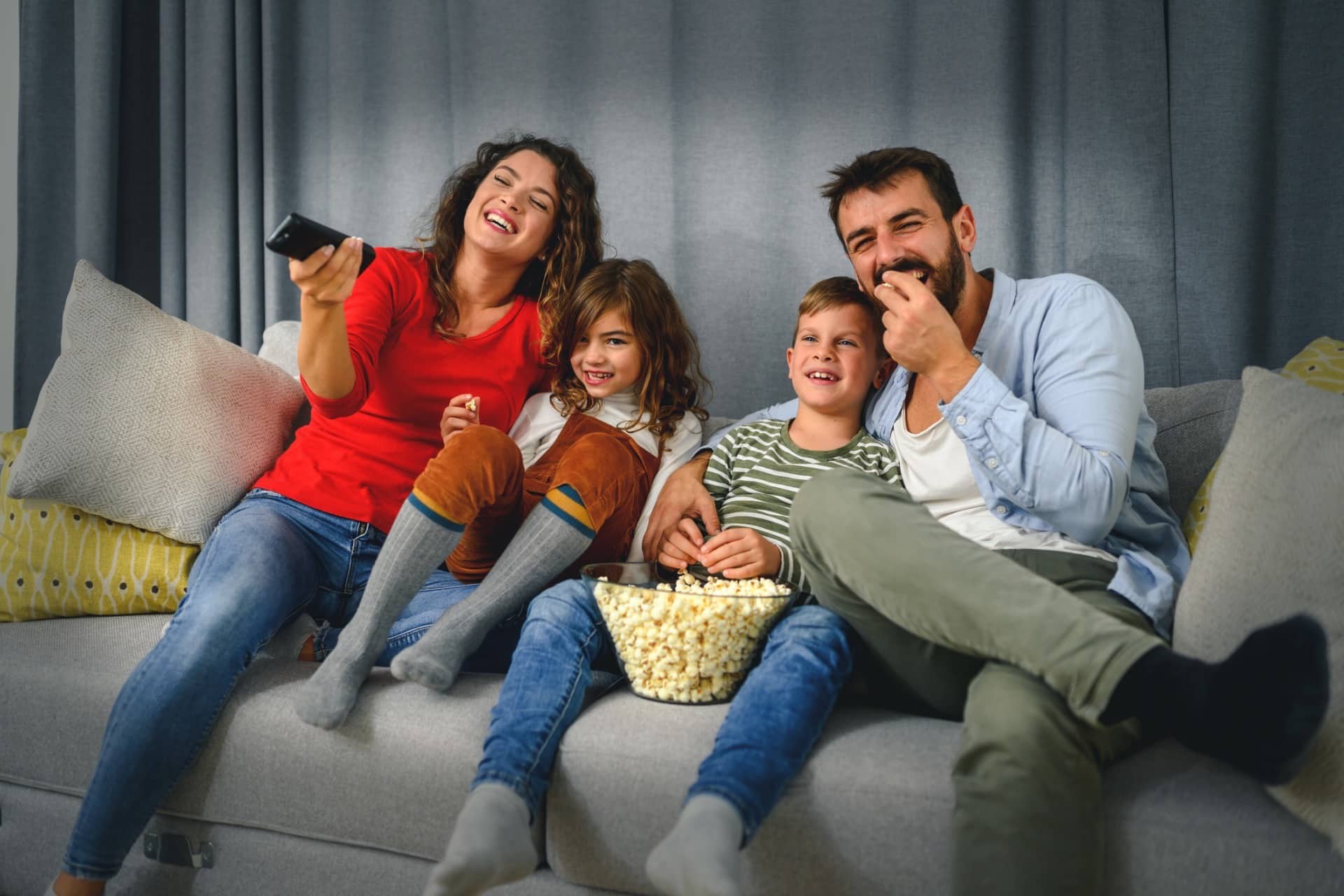 A family eating popcorn and watching a movie as a fun summertime activity.