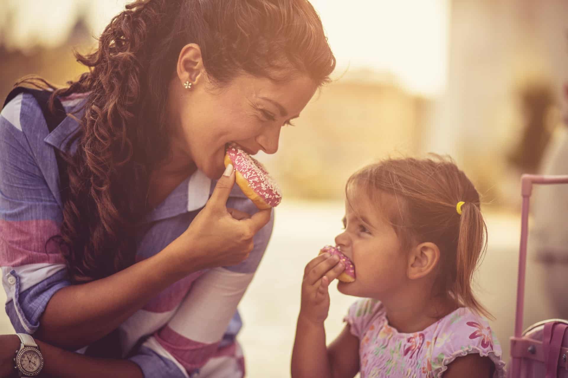 This is a photo of a mom and her daughter eating doughnuts.
